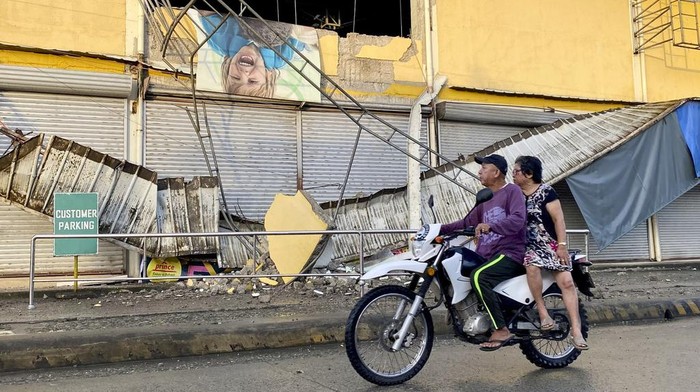 Situasi di Filipina Pasca Diguncang Gempa M 7,4 A resident walks past a toppled house caused by an earthquake at Hinatuan town, Surigao del Sur province, southern Philippines on Sunday Dec. 3, 2023. A powerful earthquake struck Saturday off the southern Philippine coast, prompting many villagers to flee their homes in panic around midnight after Philippine authorities issued a tsunami warning. (AP Photo/Ivy Marie Mangadlao)