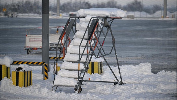A tail fin of a Lufthansa plane is pictures behind snow at the terminal as Munich Airport has cancelled all incoming and outgoing flights until 12 p.m. (1100GMT) due to a forecast for sleet in Munich, Germany, December 5, 2023. Picture taken through a fence.     REUTERS/Angelika Warmuth