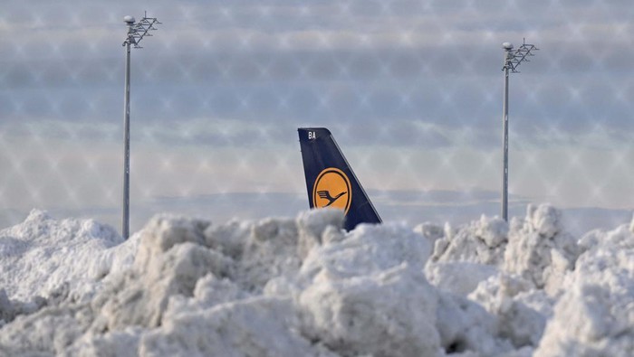 A tail fin of a Lufthansa plane is pictures behind snow at the terminal as Munich Airport has cancelled all incoming and outgoing flights until 12 p.m. (1100GMT) due to a forecast for sleet in Munich, Germany, December 5, 2023. Picture taken through a fence. REUTERS/Angelika Warmuth