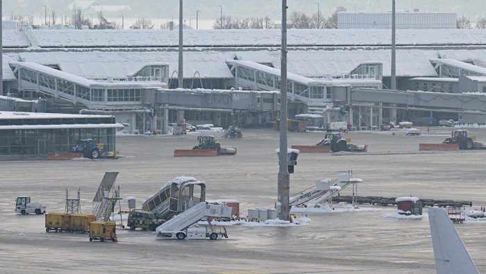 Bandara Munich Tertutup Salju, Penerbangan Dibatalkan A tail fin of a Lufthansa plane is pictures behind snow at the terminal as Munich Airport has cancelled all incoming and outgoing flights until 12 p.m. (1100GMT) due to a forecast for sleet in Munich, Germany, December 5, 2023. Picture taken through a fence. REUTERS/Angelika Warmuth