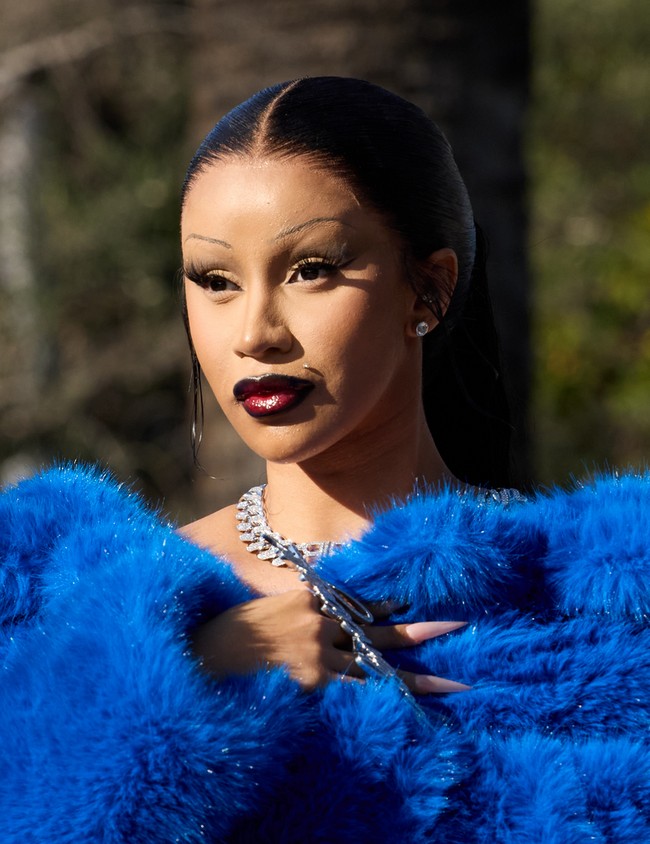 Rambutnya disisir ke belakang dan dikuncir kuda. Sementara wajahnya dipulas makeup cat-eye yang dramatis dan lipstik merah gelap. Foto: Dok. Balenciaga, Instagram/@iamcardib