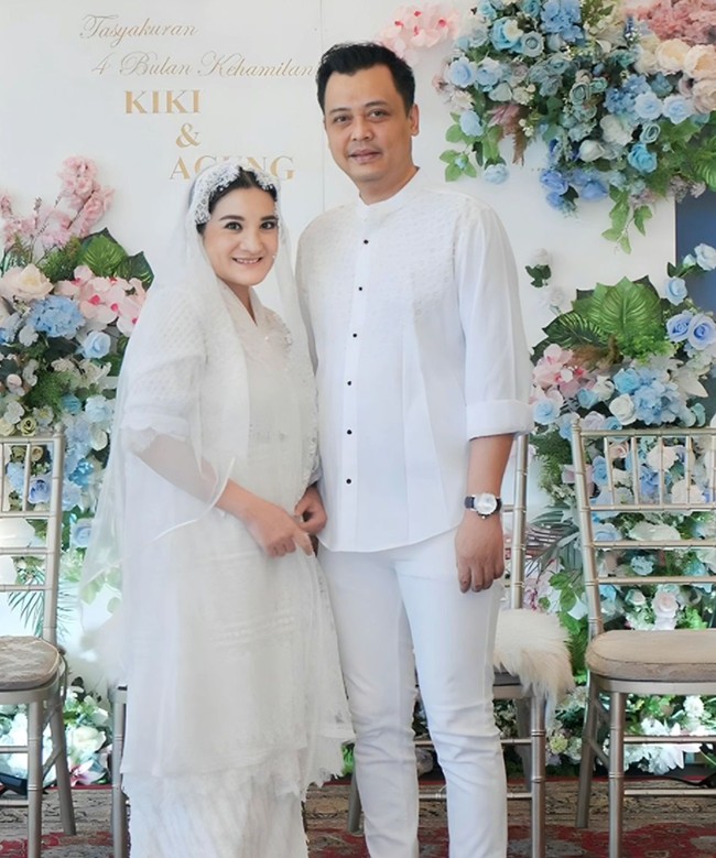 Kiki dan suaminya tampil kompak mengenakan busana serba putih. Dengan kehamilan yang sudah membesar, wajah Kiki juga terlihat mulai semakin chubby. Foto: Instagram/@kikiamaliaworld