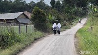 Dua orang pelajar SMP di Nagari Lasi sedang berjalan diatas aspal yang dipenuhi debu vulkanik.