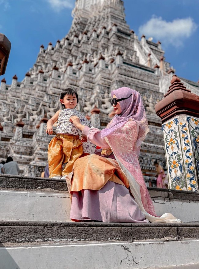 Kerap bergaya nyeleneh, potret Ria Ricis saat menggunakan kaca mata hitam terbalik sedang merapikan baju sang anak. Dalam keterangan unggahannya Ricis menulis, “Hidup kadang di atas kadang digidaw.” Foto: Instagram/@riaricis1795