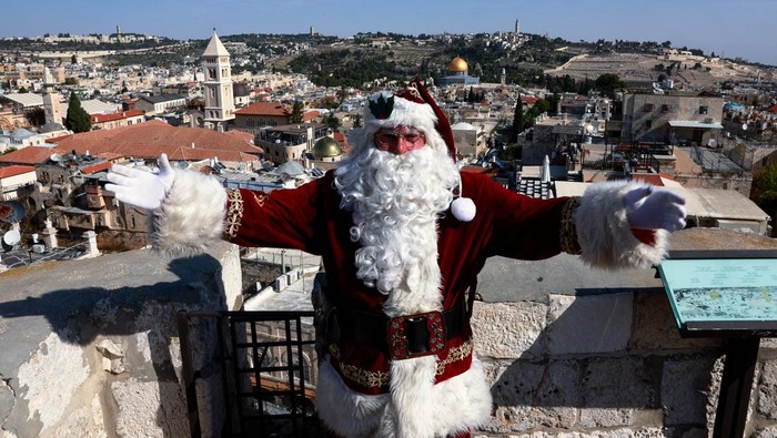 Sinterklas Naik Unta Keliling Yerusalem untuk Serukan Perdamaian Issa Kassissieh, dressed as Santa Claus, sits astride a camel as he visits an olive grove overlooking the Dome of the Rock on Al-Aqsa compound, also known to Jews as the Temple Mount, in Jerusalem, December 4, 2023. REUTERS/Ammar Awad TPX IMAGES OF THE DAY