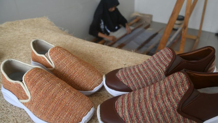 Kreatif! Limbah Tandan Sawit Disulap Jadi Bahan Baku Fesyen Pekerja menggunakan alat tenun bukan mesin (ATBM) untuk membuat kain dari limbah serat tandan kosong kelapa sawit di Kelurahan Situgede, Kota Bogor, Jawa Barat, Selasa (5/12/2023). Peneliti IPB University dari Departemen Fisika, Fakultas Matematika dan Ilmu Pengetahuan Alam (FMIPA) Siti Nikmatin mengembangkan pengolahan limbah serat tandan kosong kelapa sawit menjadi produk bernilai ekonomi yang hasilnya mulai dari inovasi rayon viskosa (kapas buatan) sebagai bahan baku industri mode (fashion) hingga sepatu dan kain tenun. ANTARA FOTO/Arif Firmansyah/aww.