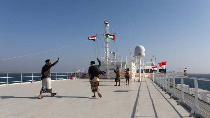 People ride a boat near the Galaxy Leader commercial ship, seized by Yemens Houthis last month, off the coast of al-Salif, Yemen December 5, 2023. REUTERS/Khaled Abdullah