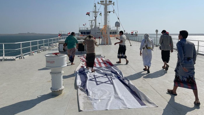 People ride a boat near the Galaxy Leader commercial ship, seized by Yemens Houthis last month, off the coast of al-Salif, Yemen December 5, 2023. REUTERS/Khaled Abdullah