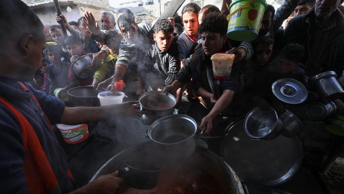 Palestinians gather to get their share of charity food offered by volunteers, amid food shortages, as the conflict between Israel and the Palestinian Islamist group Hamas continues, in Rafah, in the southern Gaza Strip, December 2, 2023. REUTERS/Ibraheem Abu Mustafa