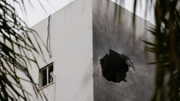 People stand next to a building which was hit by a rocket fired from Gaza today, amid the ongoing conflict between Israel and the Palestinian Islamist group Hamas, in Ashkelon, Israel, December 5, 2023. REUTERS/Amir Cohen      TPX IMAGES OF THE DAY