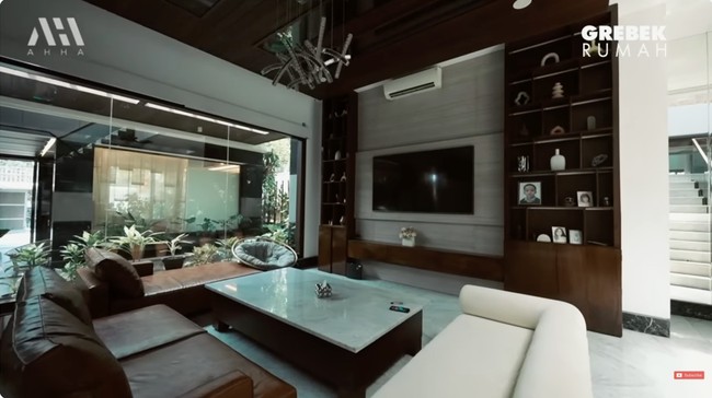 Minimalis menjadi gaya arsitektur rumahnya. Kayu mendominasi interior sehingga menciptakan atmosfer yang hangat, seperti yang terlihat di area ruang keluarga. (Foto: YouTube/AH)