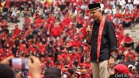 Pada kesempatan tersebut Ganjar terlihat mengenakan kemeja hitam dipadu dengan celana panjang krem lengkap dengan peci hitam dan selendang berwarna merah yang khas.