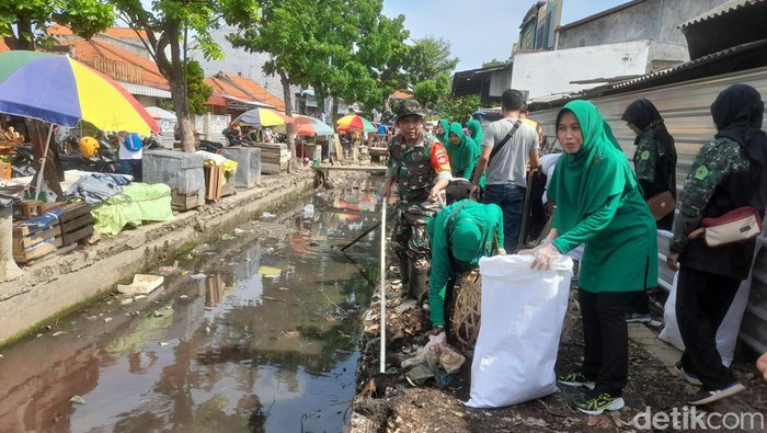Personel Kodim 0713/Brebes dibantu masyarakat menggelar aksi bersih-bersih sampah yang menyumbat saluran irigasi sekitar Pasar Kodim Brebes.