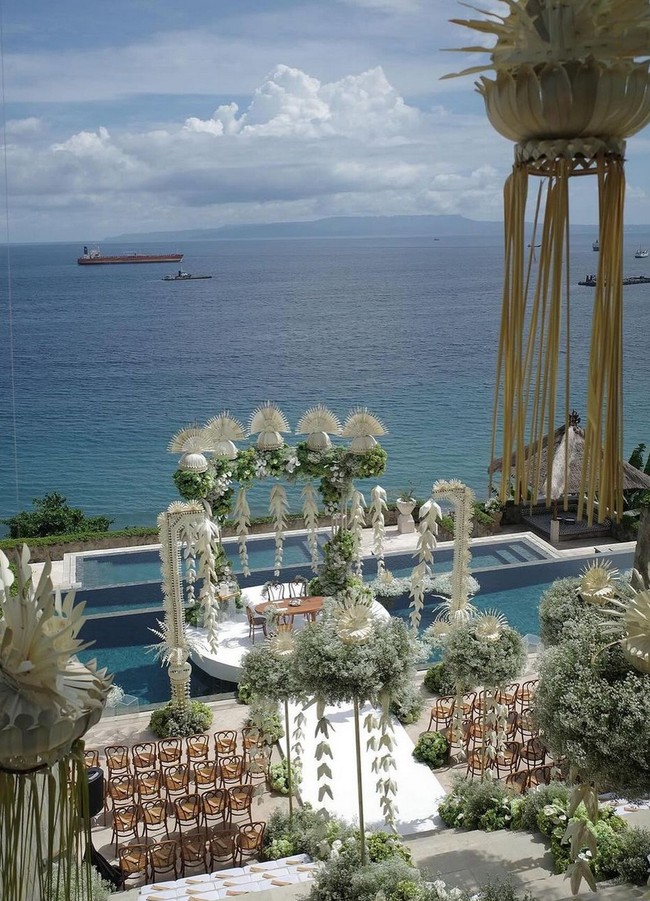 Bebungaan putih dan dedaunan hijau mendominasi wedding venue yang berbatasan langsung dengan lautan di resort mewah Amankila, Bali. Foto: Instagram/@stupacaspea @lxemoments