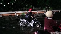 Pengendara mendorong motornya akibat melintasi genangan di Jalan Bung Tomo, setelah hujan lebat melanda Kota Surabaya.