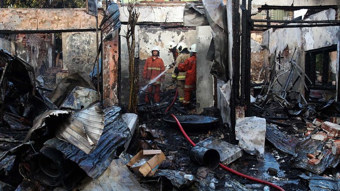 Petugas Dinas Pemadam Kebakaran dan Penyelamatan (DPKP) Kota Surabaya melakukan pembasahan pada sejumlah toko yang terbakar di Jalan Patmosusastro, Surabaya, Jawa Timur, Kamis (7/12/2023). Sebanyak 18 kendaraan pemadam kebakaran DPKP Kota Surabaya dikerahkan untuk memadamkan kebakaran enam bangunan yang digunakan sebagai tempat usaha pembuatan abon serta penjualan barang-barang antik. ANTARA FOTO/Didik Suhartono/aww.