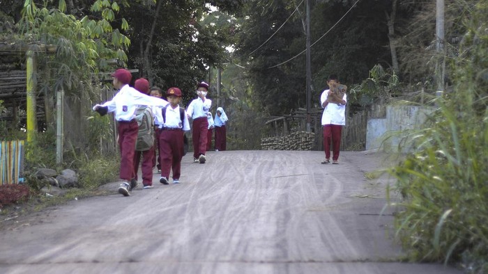 Potret Aktivitas Warga Lereng Marapi Saat Erupsi School children walk on a road covered in volcanic ash from the eruption of Mount Marapi in Agam, West Sumatra, Indonesia, Tuesday, Dec. 5, 2023. Rescuers searching the hazardous slopes of the volcano found more bodies of climbers who were caught by a surprise weekend eruption, raising the number of confirmed dead to nearly two dozens, officials said Tuesday. (AP Photo/Wica Harefa)