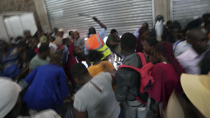 Potret Warga Zimbabwe Desak-desakkan demi Dapat Kerja A security guard uses a baton to control young people at a government jobs fair in Harare, Wednesday, Dec. 6, 2023. A stampede at a government-organized job fair involving hundreds of young people in Zimbabwe desperate for work has left some limping and others screaming in pain after being stomped on or beaten by security guards Wednesday. (AP Photo/ Tsvangirayi Mukwazhi)
