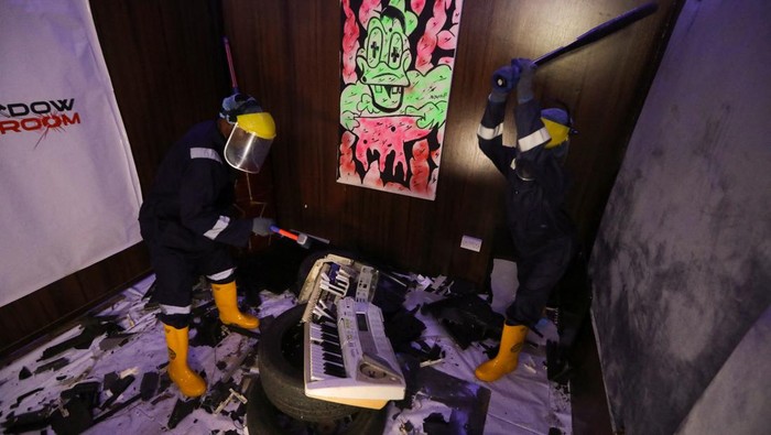 People smash a musical keyboard at the Shadow rage room, a place where people can destroy objects to vent anger, in Lagos, Nigeria October 15, 2023. REUTERS/Temilade Adelaja