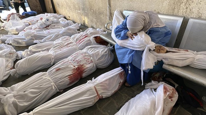 A Palestinian woman reacts over the body of a child as she sits by bodies of Palestinians killed by Israeli airstrikes on Jabaliya refugee camp, at the Indonesian hospital, northern Gaza Strip, Saturday, Nov. 18, 2023. (AP Photo/Ahmed Alarini)