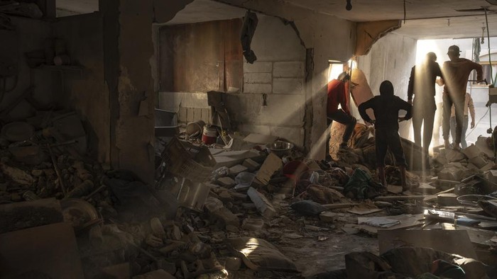 2 Bulan Dibombardir Israel, Korban Tewas di Gaza Tembus 17 Ribu Orang Palestinians go through a house destroyed during an Israeli bombardment in Rafah, Gaza Strip, Thursday, Dec. 7, 2023. (AP Photo/Fatima Shbair)