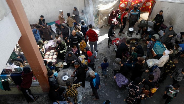 Displaced Palestinians cook at a school sheltering people who fled their houses due to Israeli strikes, in Rafah in the southern Gaza Strip, December 7, 2023. REUTERS/Saleh Salem