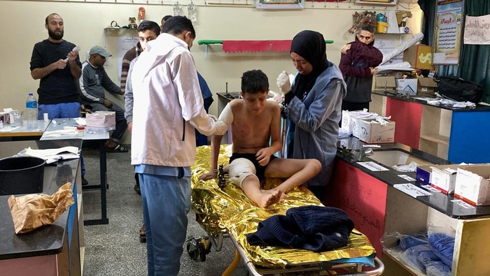 Israel Makin Brutal, Warga Gaza Mengungsi ke Bangunan Sekolah di Rafah A boy reacts while he is assisted, as Palestinians wounded in Israeli strikes shelter in a school where they experience food shortages, near Rafah in the southern Gaza Strip December 7, 2023. REUTERS/Arafat Barbakh