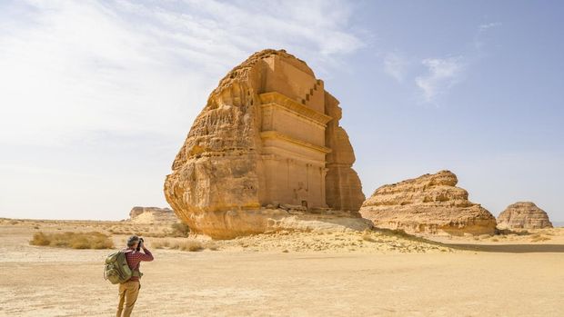 Turis dengan ransel memotret ikon Makam Lihyan, Putra Kuza, ruang pemakaman yang dipahat menjadi formasi batuan di Madain Saleh atau Hegra.