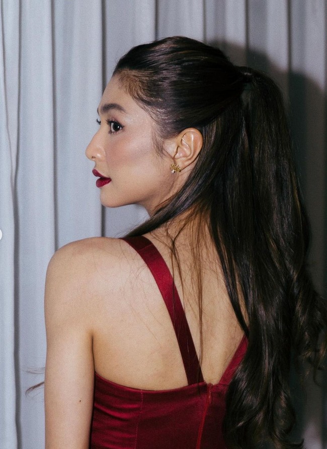 Riasan wajah wanita 29 tahun ini dibuat lebih glamor dengan pulasan lipstik merah gelap.  Foto: Instagram/@miktambayong @bagusboker