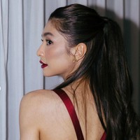 Riasan wajah wanita 29 tahun ini dibuat lebih glamor dengan pulasan lipstik merah gelap.  Foto: Instagram/@miktambayong @bagusboker