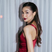 Untuk acara malam hari, Mikha Tambayong berganti busana dengan gaun merah marun berbahan satin. Gaun bergaya V-neck ini minim detail namun tetap terlihat elegan dari bahan satin. Foto: Instagram/@miktambayong @bagusboker