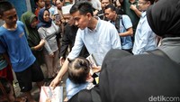 Selama perjalanan menuju panggung, Gibran turut menyapa warga yang menyambutnya sambil membagikan buku tulis dan susu untuk anak-anak.