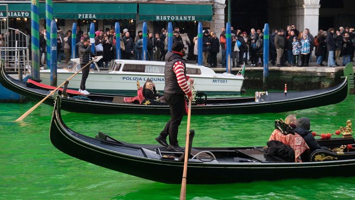 People ride in boats as waters of Grand Canal turned green after a protest by Extinction Rebellion climate activists in Venice, Italy, December 9, 2023. REUTERS/Manuel Silvestri