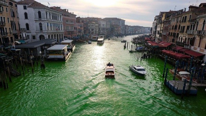 Aktivis Iklim Bikin Air Kanal Venesia Hijau Protes KTT COP28 People ride in boats as waters of Grand Canal turned green after a protest by 'Extinction Rebellion' climate activists in Venice, Italy, December 9, 2023. REUTERS/Manuel Silvestri