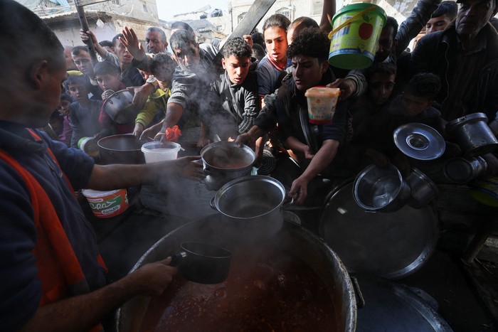 A Palestinian child reacts, while people gather to get their share of charity food offered by volunteers, amid food shortages, as the conflict between Israel and the Palestinian Islamist group Hamas continues, in Rafah, in the southern Gaza Strip, December 2, 2023. REUTERS/Ibraheem Abu Mustafa