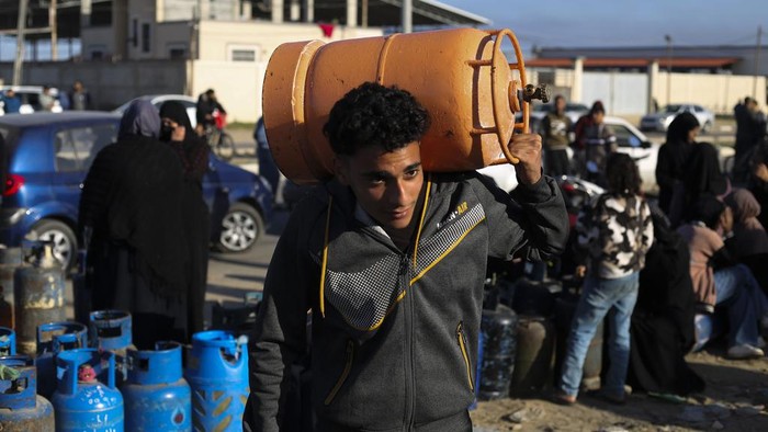 Palestinias line up for cooking gas during the ongoing Israeli bombardment of the Gaza Strip in Rafah on Sunday, Dec. 10, 2023. (AP Photo/Hatem Ali)