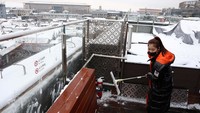 Seorang pekerja membersihkan rooftop sebuah restoran dari tumpukan salju di Beijing.  