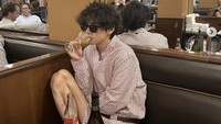 Dengan pose mengantuk, V BTS pamer momen sedang minum champagne dan makan di restoran mewah. Terlihat ada roti dan salad di hadapannya. Foto: Instagram thv