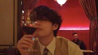 Momen lain V BTS di restoran mewah terlihat pada foto ini. Ia menggunakan pakaian resmi sambil menikmati segelas red wine. Foto: Instagram thv