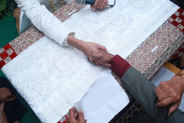 Muslim wedding ceremony. The marriage process for Indonesian Muslim bride-to-be is called Ijab Kabul in Akad Nikah. handshake between the groom and the brides father.