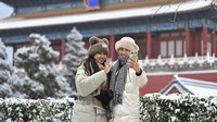 Meski begitu, tak sedikit warga China mengabadikan momen salju pertama yang turun di Beijing di awal musim yang lebih dingin ini. (Li Xin/Xinhua via AP)