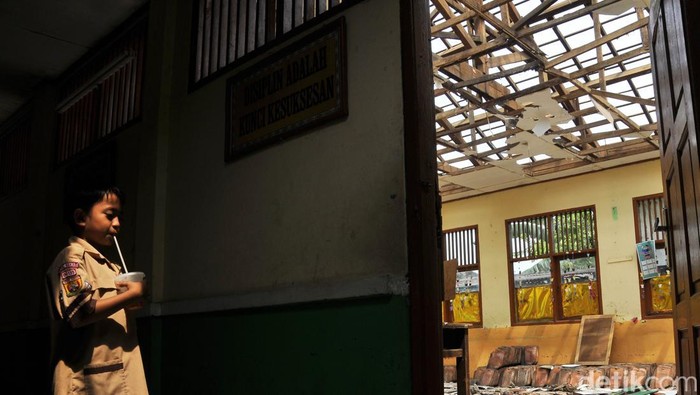 Seorang murid SDN Setiamekar 03 mengamati atap ruang kelas yang roboh di Tambun, Kabupaten Bekasi, Jawa Barat, Selasa (12/12/2023). Menurut pihak sekolah atap dua ruang kelas tersebut roboh pada Jumat (8/12) dan untuk sementara siswa belajar secara bergantian di tiga ruang kelas tersisa dengan dibatasi waktu selama 3 jam. ANTARA FOTO/ Fakhri Hermansyah/rwa.