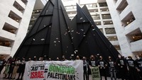 Massa berkasi dengan membentangkan spanduk bertuliskan Aid to Israel = bombing Palestinians, Senin (11/12/2023).