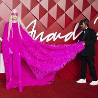 Eksis di British Fashion Awards 2022, ibu empat anak ini bersolek dalam balutan gaun merah muda mencolok Valentino yang dilengkapi jubah dramatis penuh bulu. Gayanya makin eksentrik berkat bulu mata ekstrem. Di karpet merah, ia dibantu oleh direktur kreatif Valentino Pierpaolo Piccioli. (Foto: Vianney Le Caer/Invision/AP)