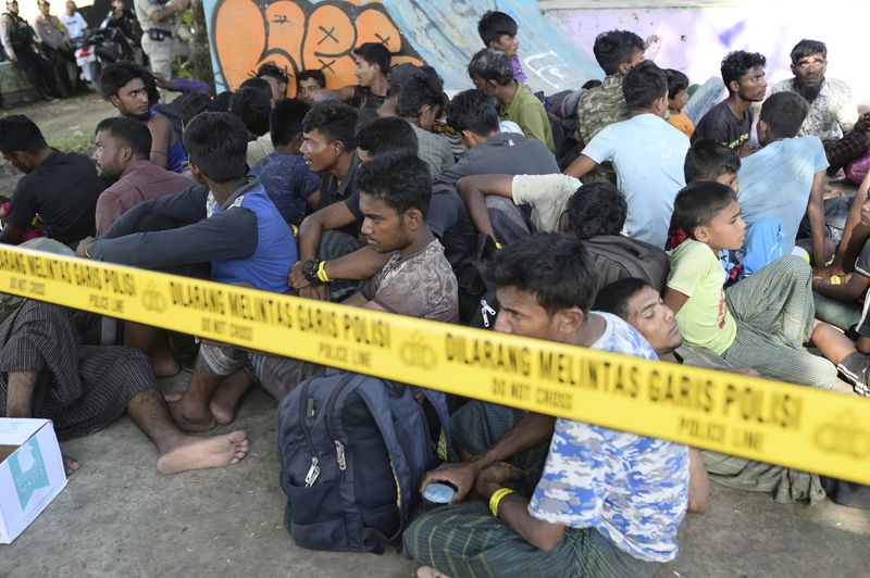 Acehnese men block the entrance gate to a temporary shelter to prevent Rohingya refugees from entering in Ladong, Aceh province, Indonesia, Monday, Dec. 11, 2023. Two boats carrying hundreds of Rohingya Muslims, including emaciated women and children, arrived on Sunday at Indonesia's northernmost province of Aceh where they faced rejection from local communities who are protesting against the increasing numbers of refugees that have entered the region over the past few weeks. (AP Photo/Reza Saifullah)