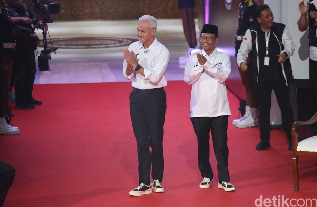 Ganjar Pranowo dan Mahfud MD meyakini kekuatan fashion dalam mengkomunikasikan aspirasinya sejak Debat Pilpres 2024 edisi pertama yang digelar di markas Komisi Pemilihan Umum (KPU) pada 12 Desember 2023. Keduanya kompak berkemeja putih dan celana panjang hitam. Tampak tulisan ‘Sat Set’ muncul di kemeja Ganjar, sementara punya Mahfud dihasi  ‘Tas Tes’. (Foto: Pradita Utama/detikcom)
