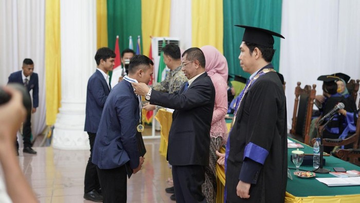 Kepala Badan Pengembangan Sumber Daya Manusia Industri (BPSDMI) Kemenperin Masrokhan (kiri) memberikan toga pelantikan wisuda SMK-Banda Aceh di Banda Aceh, Senin (11/12/2023). Kementerian Perindustrian melantik 5.673 siswa dan mahasiswa SMK, Politeknik, dan Akademi Komunitas Kemenperin sepanjang tahun 2023 dengan 87% lulusan SMK dan 74% lulusan Politeknik & Akom sudah terserap di industri.