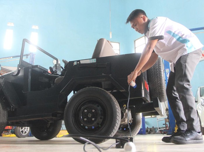 Pelajar menunjukkan cara pengisian ulang baterai mobil listrik yang diberi nama Jeep K10 di laboratorium otomotif SMK 10 Malang, Jawa Timur, Rabu (13/12/2023). Kendaraan listrik berupa motor dan mobil jip hasil inovasi pelajar tersebut menggunakan baterai rakitan bertegangan 72 volt sehingga memiliki daya penyimpanan lebih besar serta berbiaya lebih murah jika dibandingkan kendaraan listrik buatan pabrik. ANTARA FOTO/Ari Bowo Sucipto/foc.