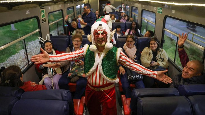 Kereta Berhias Lampu Natal Wara-wiri di Kolombia People pose for a photo next to the tourist train 'La Sabana', decorated with Christmas lights in Bogota, Colombia December 11, 2023. REUTERS/Luisa Gonzalez