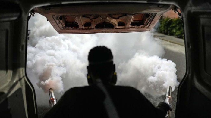 A motorcyclist drives past clouds of insecticide during a fumigation campaign against dengue-promoting mosquitoes, in the Altamira neighborhood of Caracas, Venezuela, Tuesday, Dec. 12, 2023. (AP Photo/Matias Delacroix)